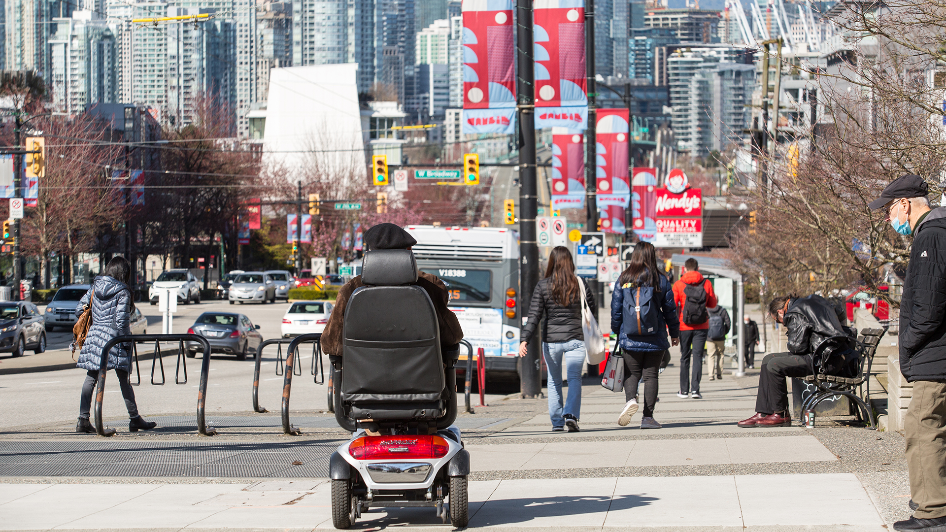 A person in a motorized wheel chair crosses a Vancouver street in March.