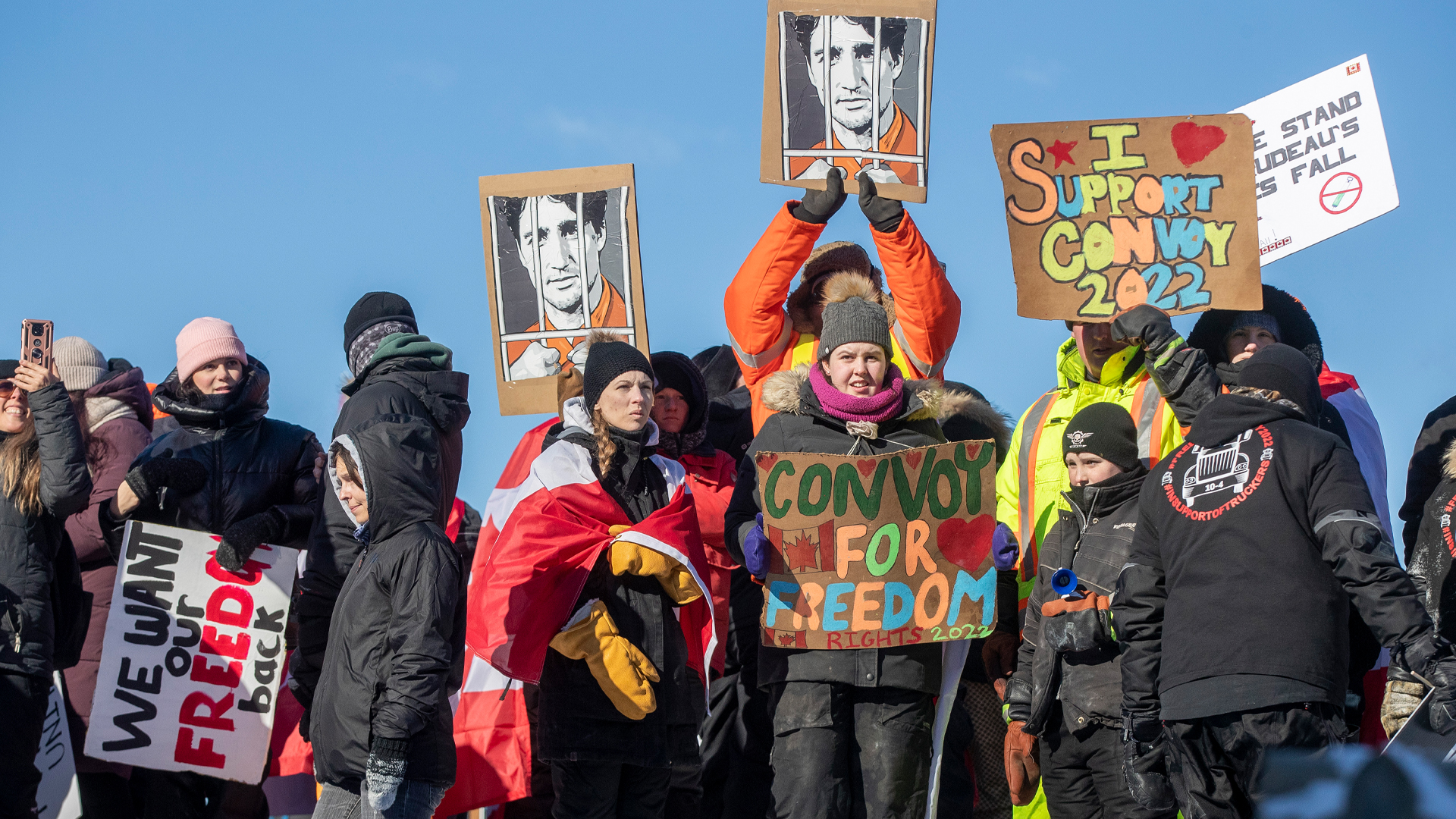 A dozen people with hand-drawn signs saying things like “we want our freedom back” as well as two cardboard drawings depicting Prime Minister Justin Trudeau behind bars.