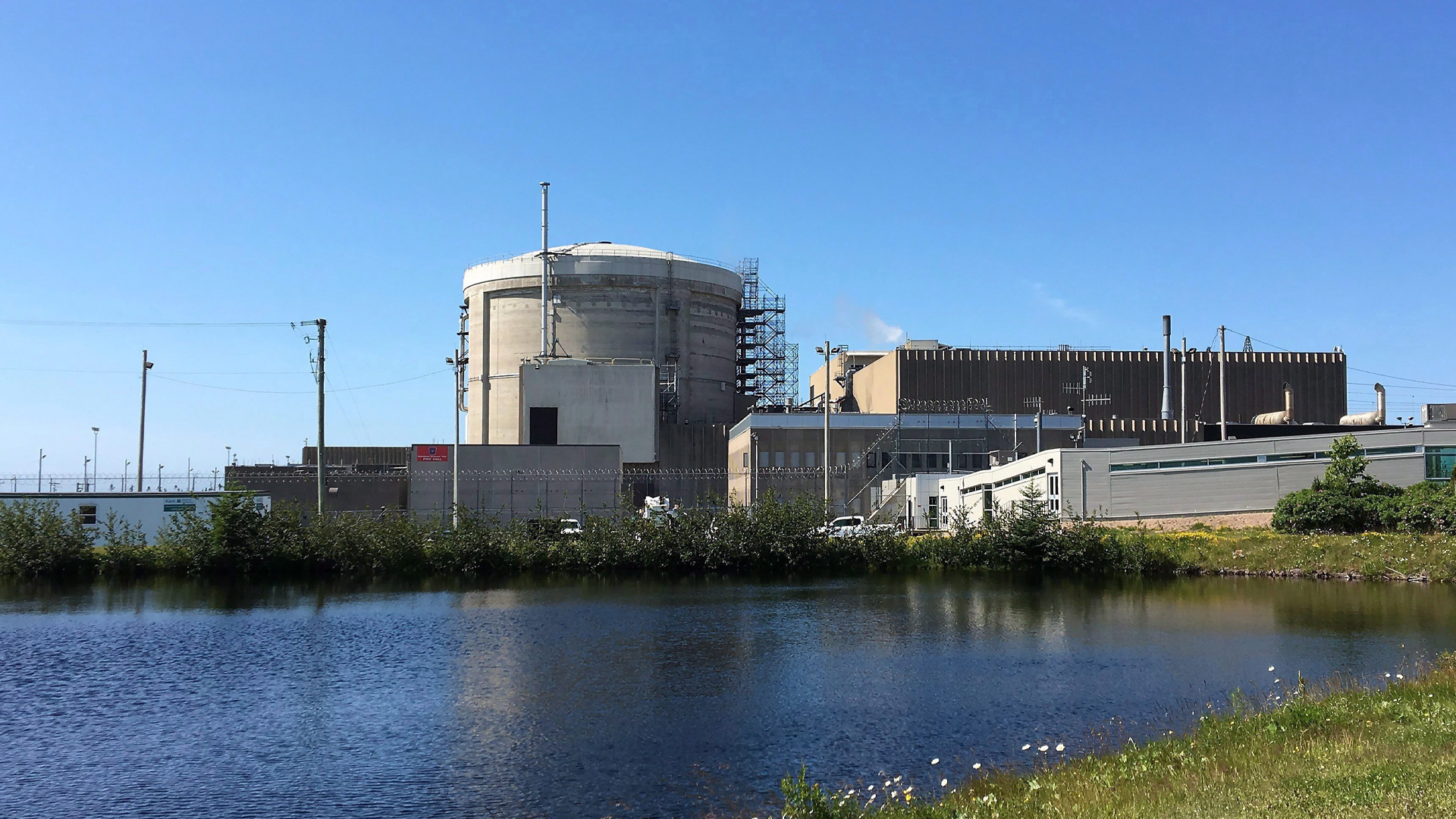A beige cluster of industrial buildings sits next to the water’s edge.