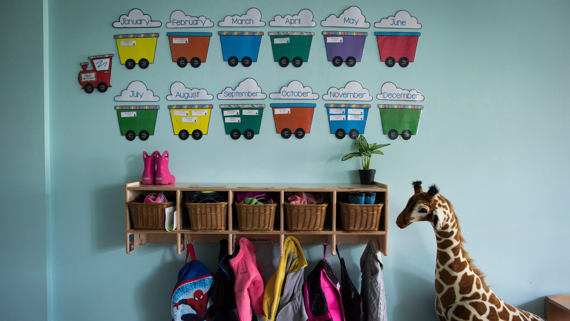 Multi-coloured car illustrations hang on a wall above small lockers with baskets and backpacks in a daycare in Langley, B.C.