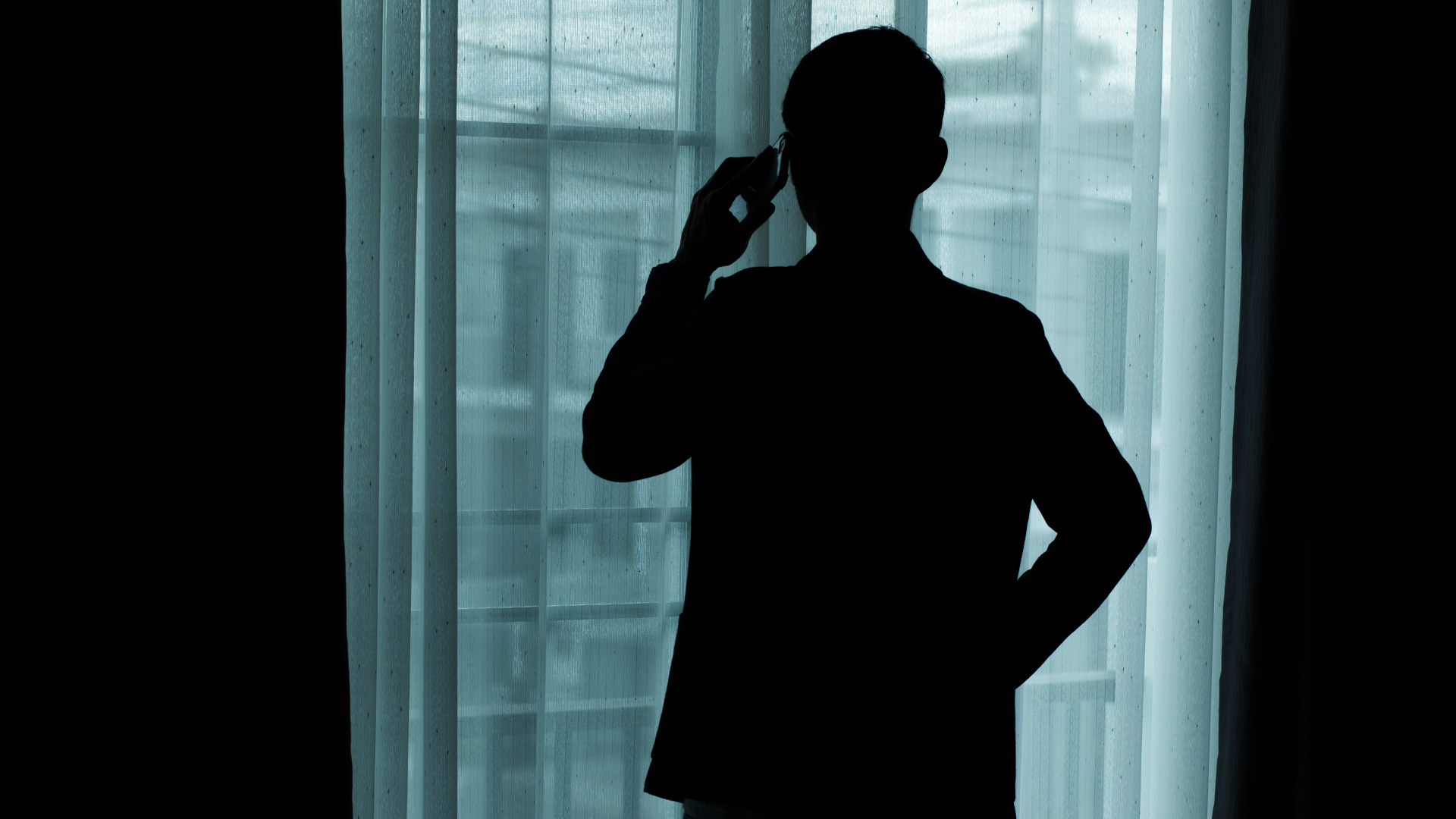 A person in dark silhouette makes a phonecall.