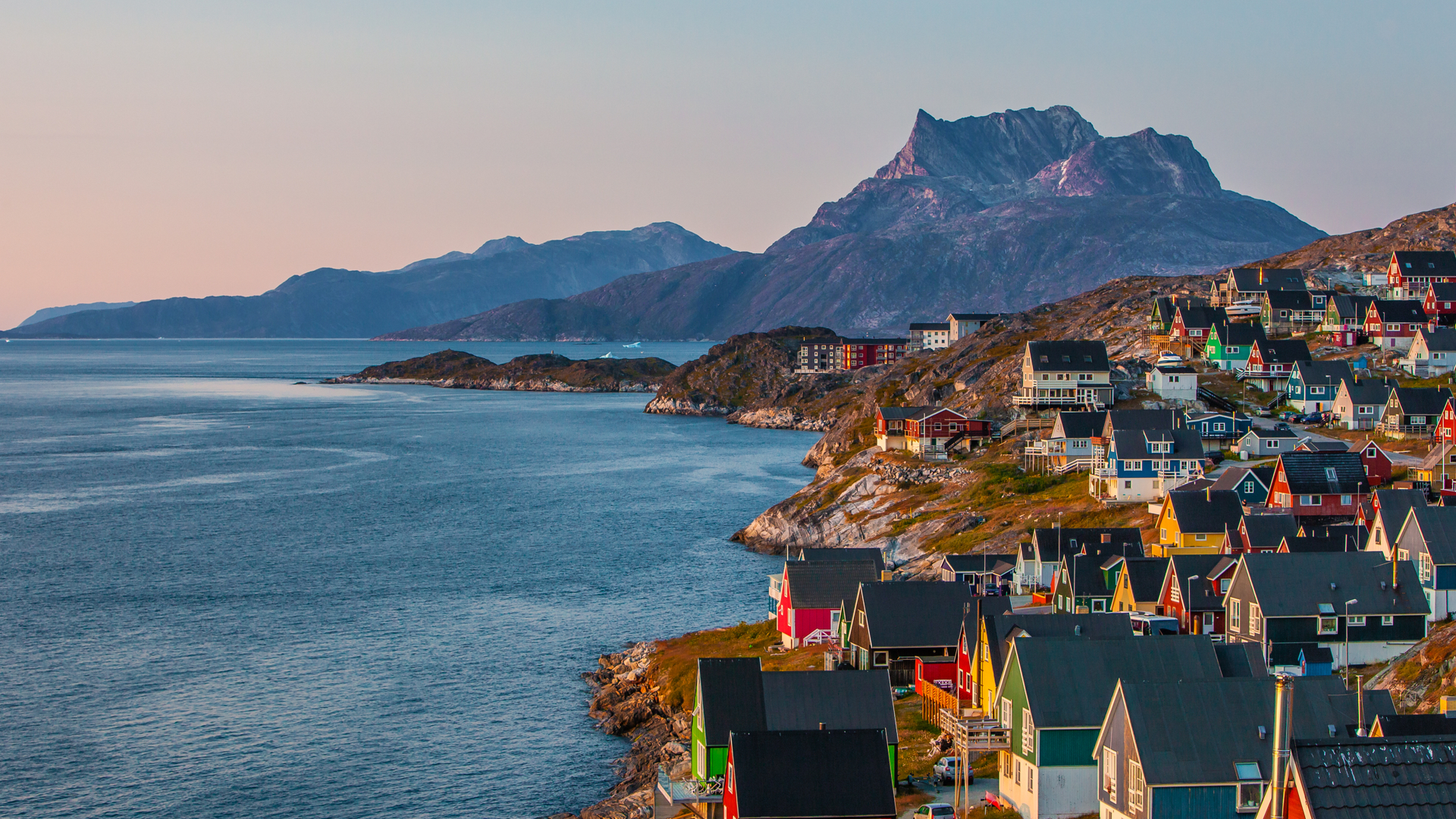 On aperçoit une côte, avec des montagnes qui s’élèvent de l’océan, sur lequel souffle un vent léger. Le long de la côte, accidentée et brune, se trouve la ville, avec son groupe de maisons à pignons aux couleurs vives, bleues, rouges, vertes et blanches. Il n’y a pas de neige.