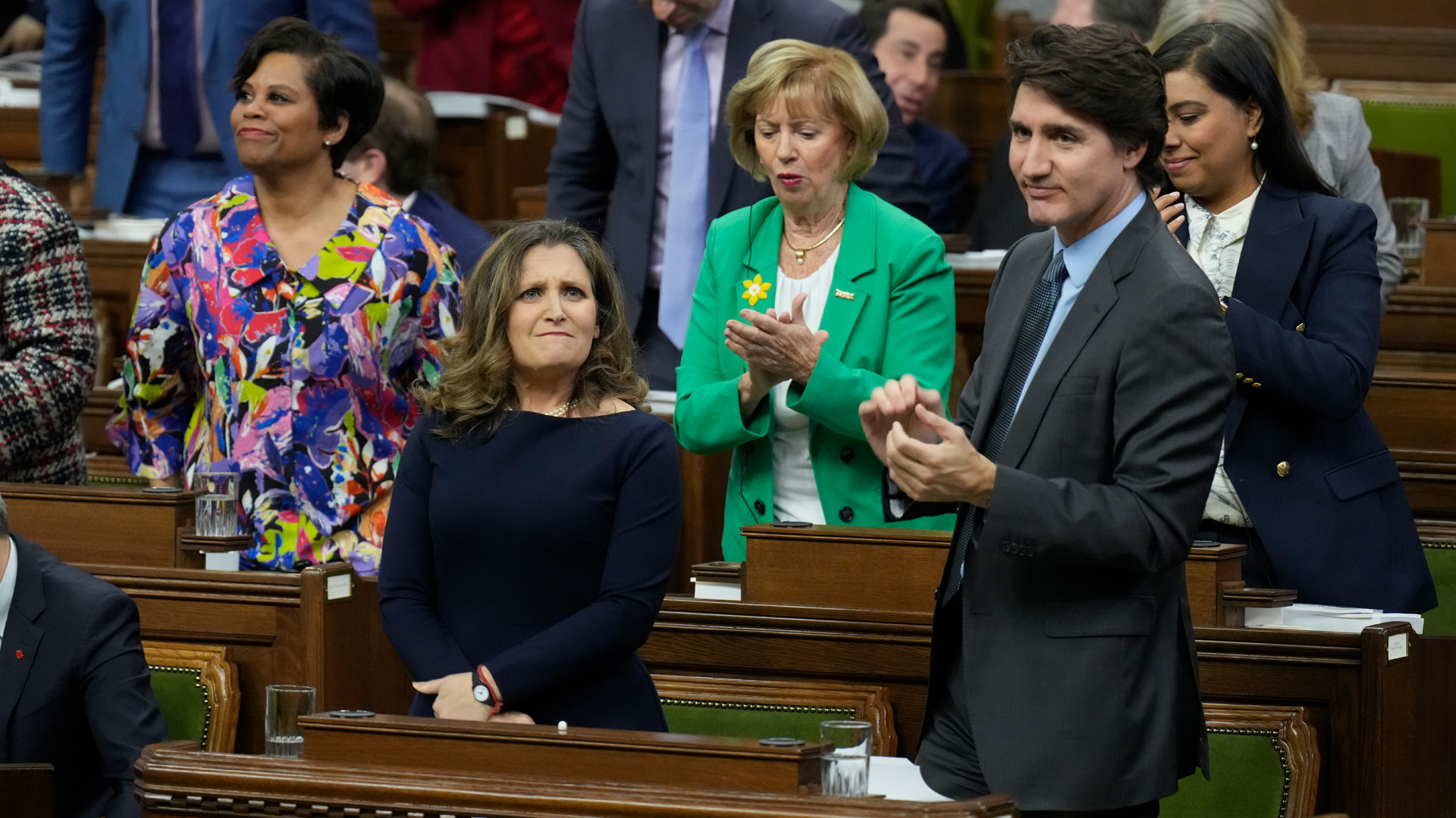 Wearing a navy dress, Deputy Prime Minister and Minister of Finance Chrystia Freeland receives applause from Prime Minister Justin Trudeau, right, and other members of the Liberal party after she presented the federal budget in the House of Commons in Ottawa on Tuesday, April 16, 2024.