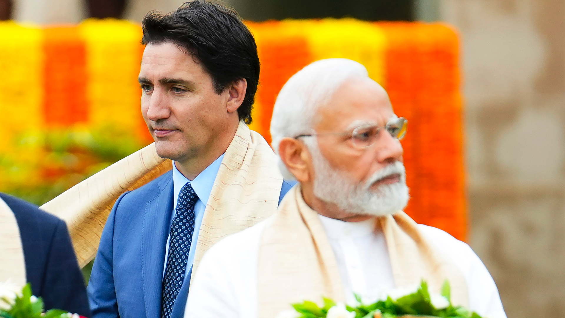 Prime Minister Justin Trudeau walks behind Indian Prime Minister Narendra Modi who is carrying a wreath.