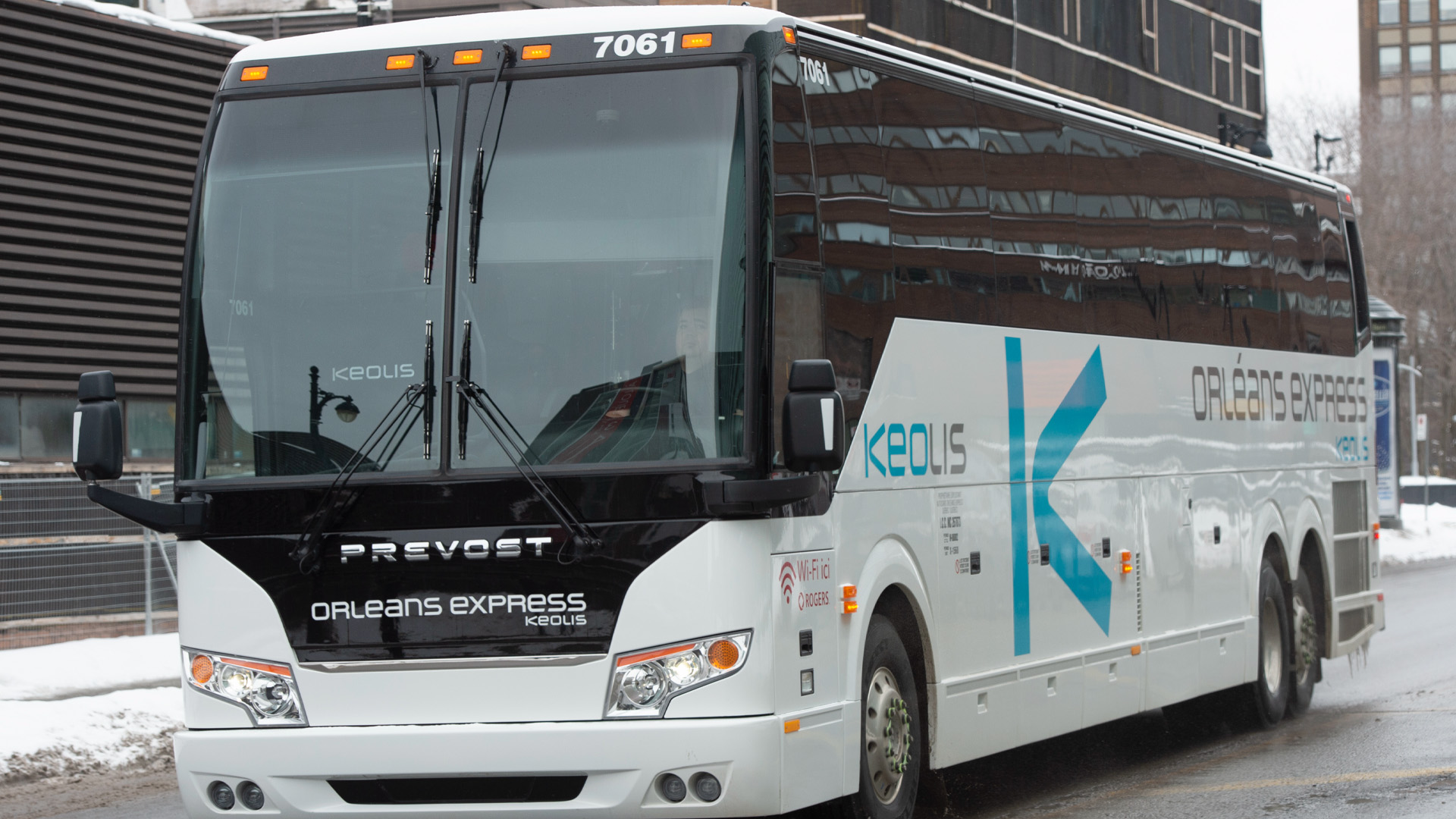 A white bus drives through the snowy streets of Montreal