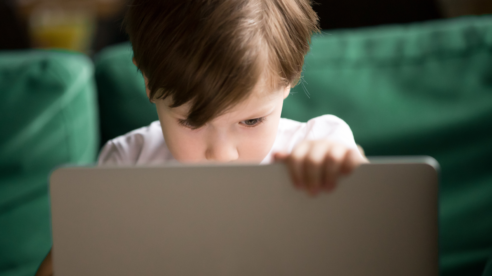 A child concentrating intently on a laptop screen.
