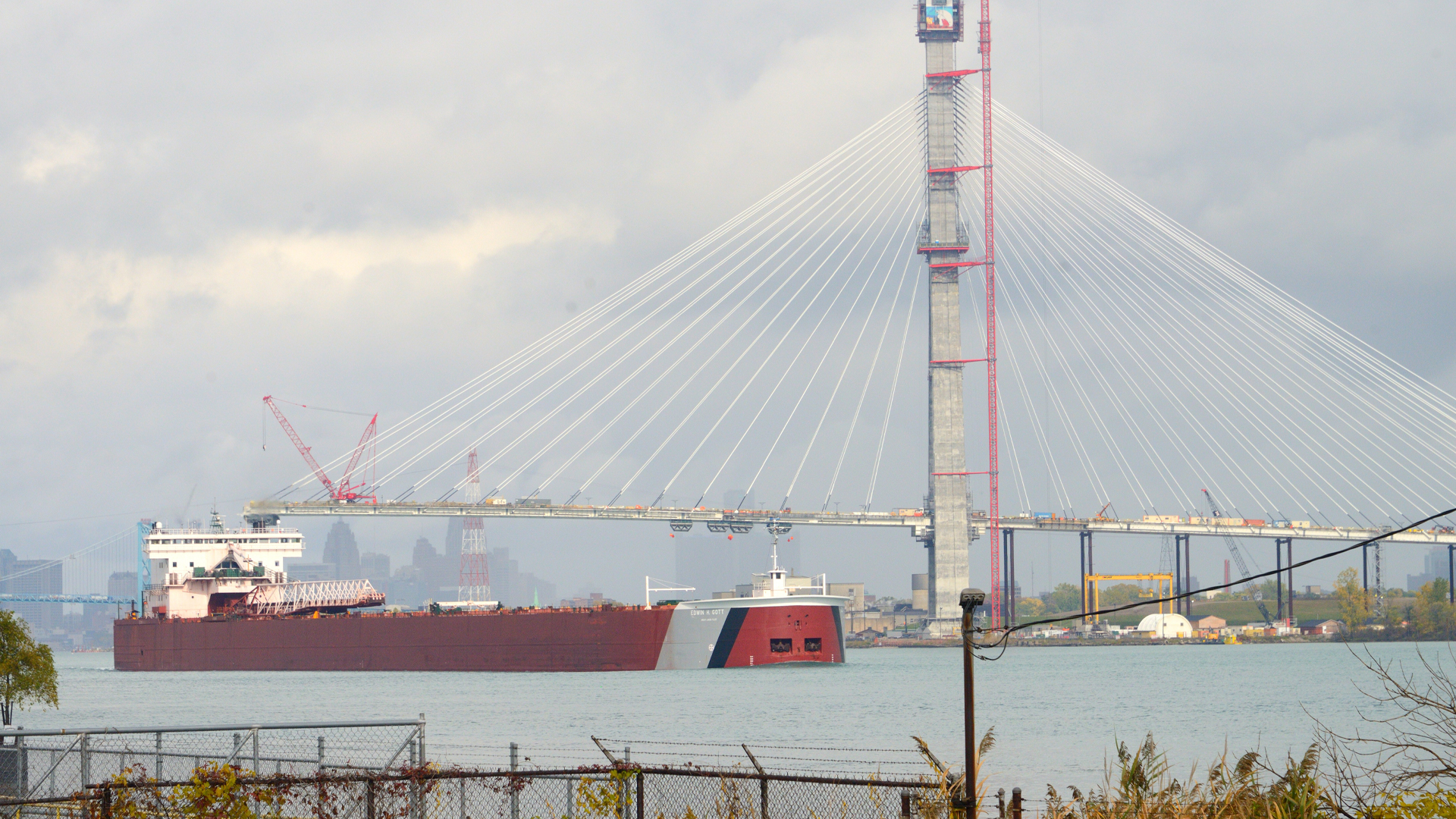 Un navire-citerne rouge passe à côté du pont partiellement construit.