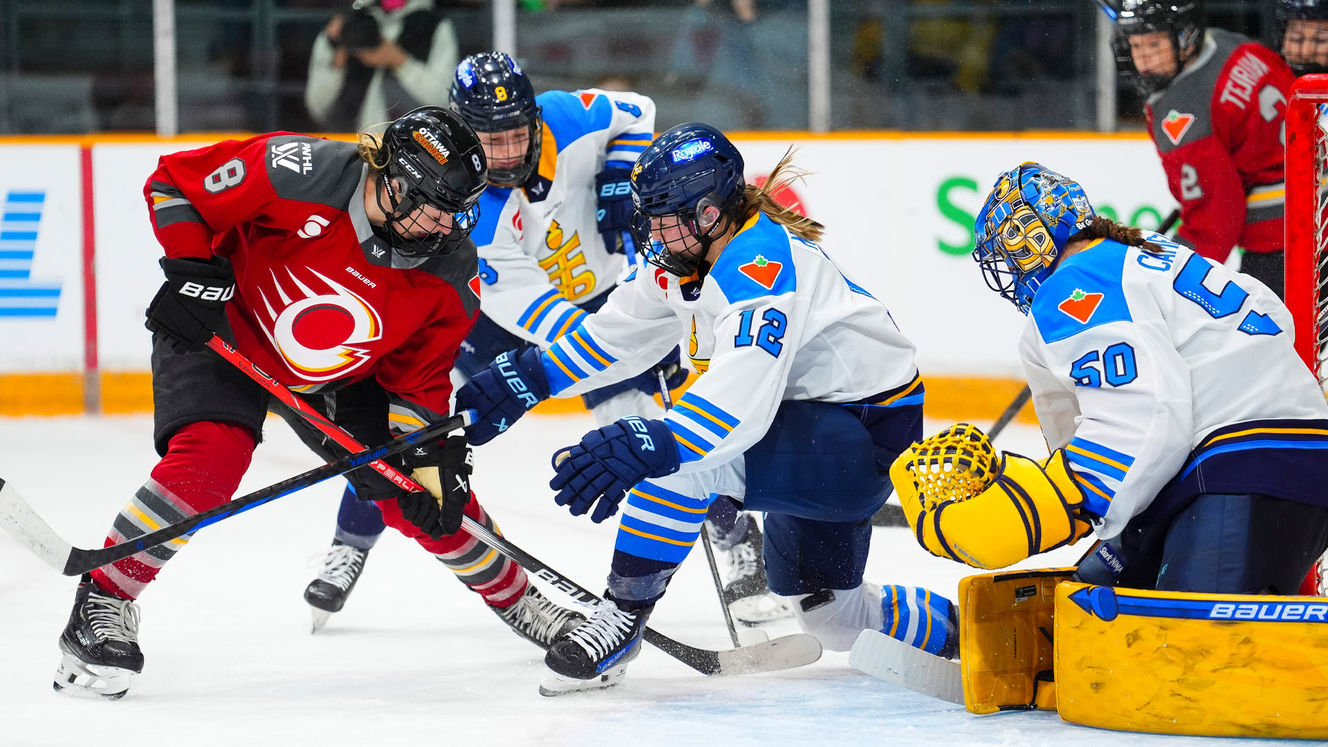 Women hockey players from the Ottawa Charge and Toronto Sceptres battle for a puck in front of the Toronto net.