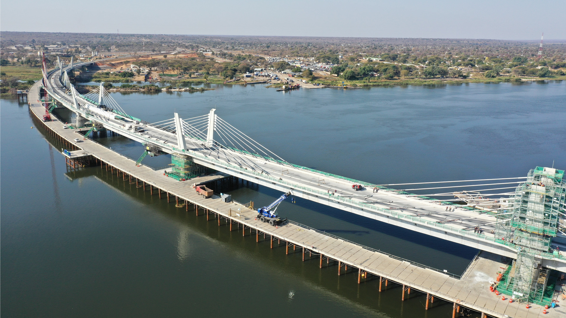 The bridge sits fairly close to the water, and has two platforms. One of them sits even lower, separate from the main platform. In the distance sits a mostly undeveloped landscape of trees.