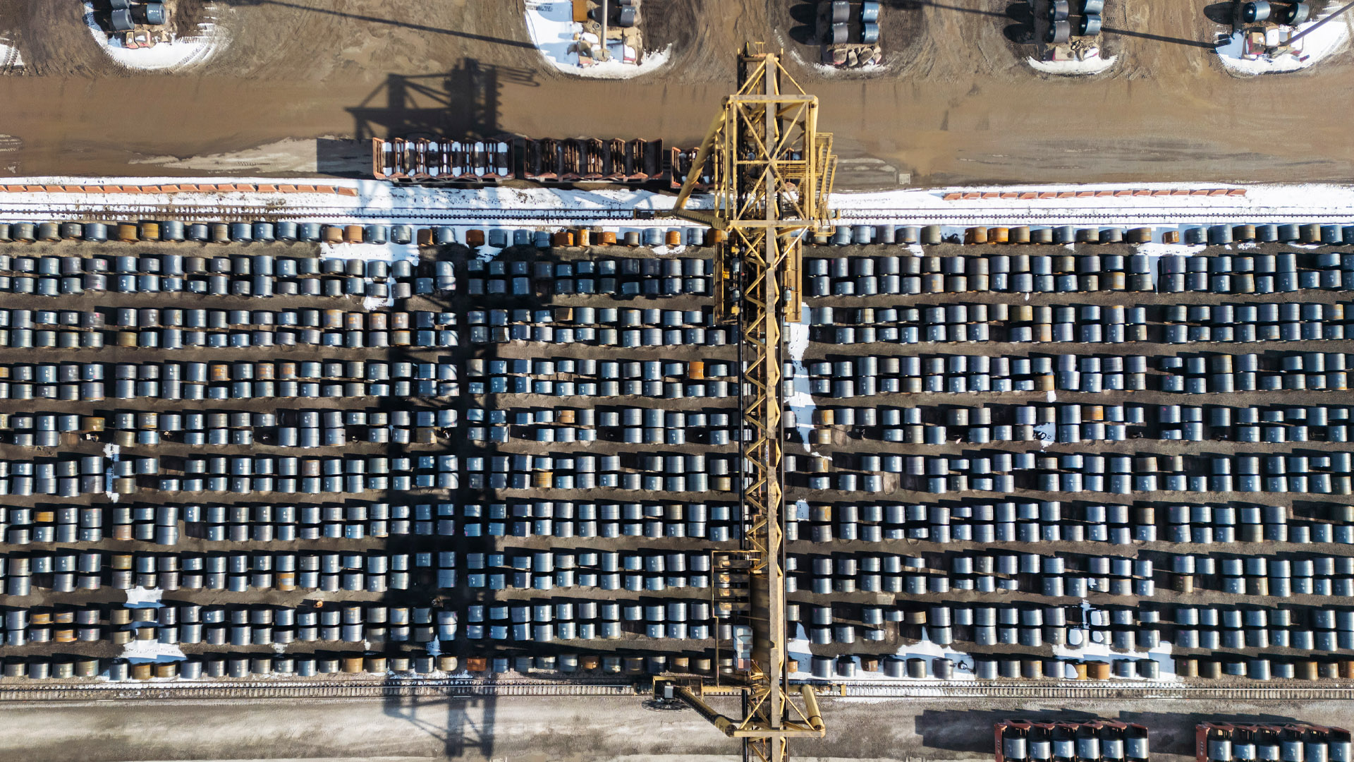 An aerial view of dozens upon dozens of steel coils lined up in an outdoor lot.