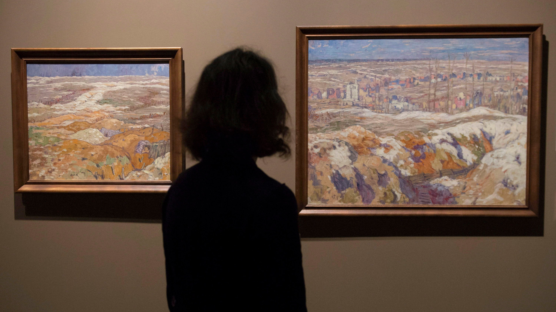 A silhouetted woman in front of two landscape paintings. 