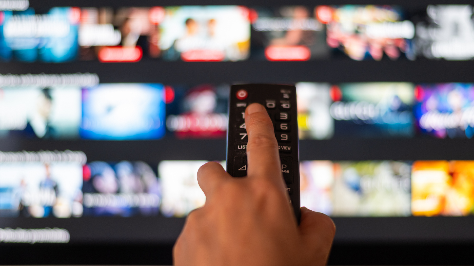 Une main tient une télécommande devant une télévision branchée sur un service de médias en continu.