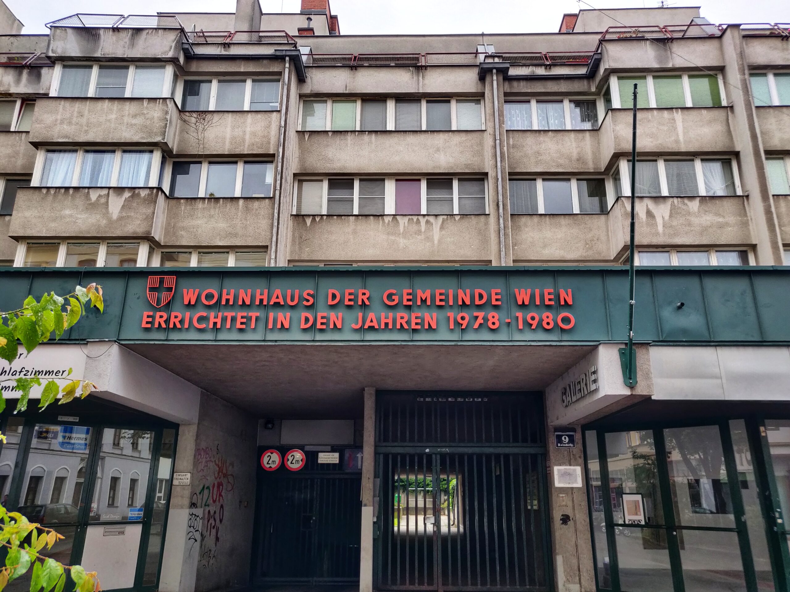 A four-storey building whose cream-coloured facade is stained with sooty material. 