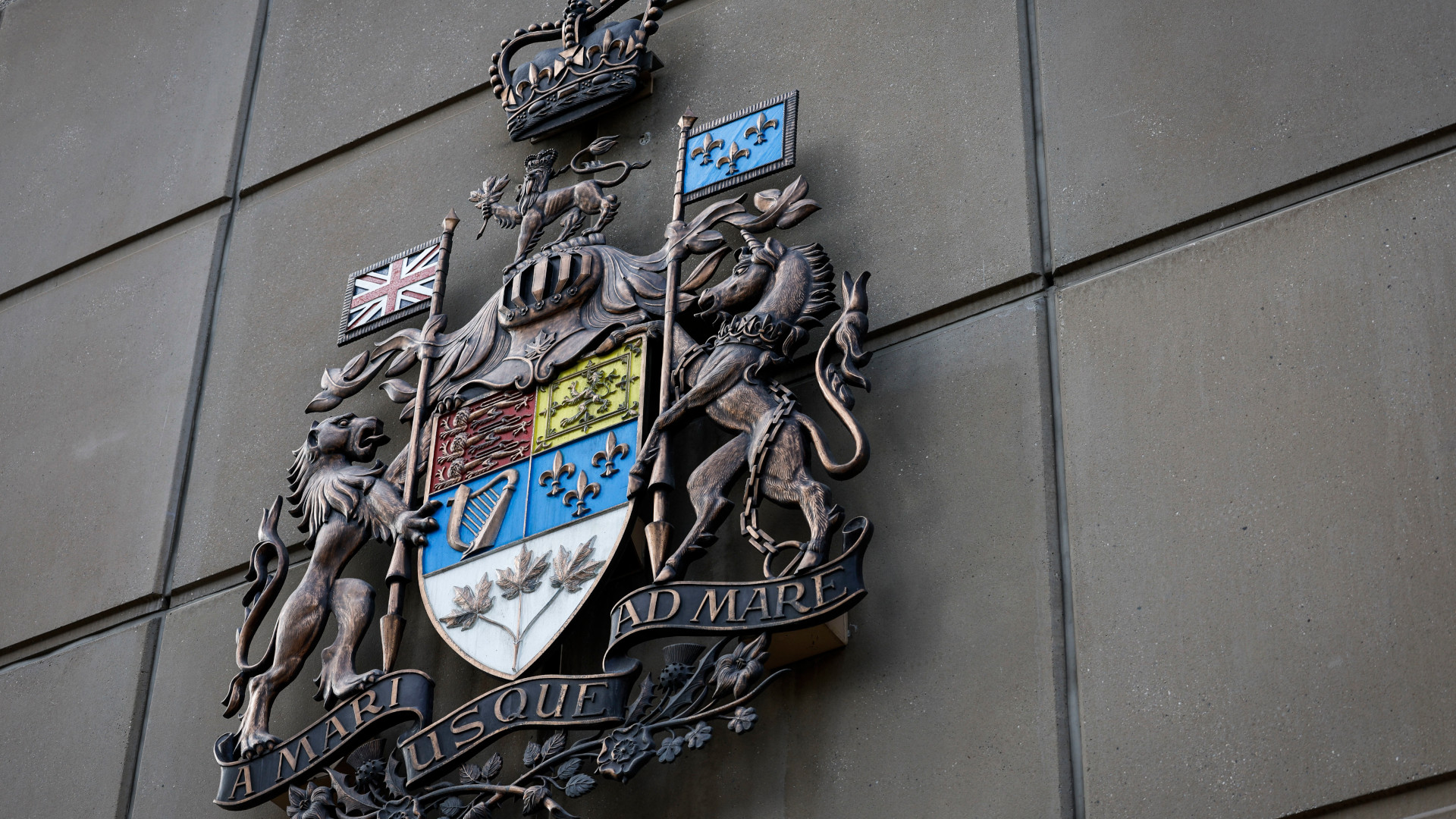 The metal crest is ornate with elements that include depictions of the fleur-de-lys, a harp, maple leaves, the Union Jack flag and a crown at the top.