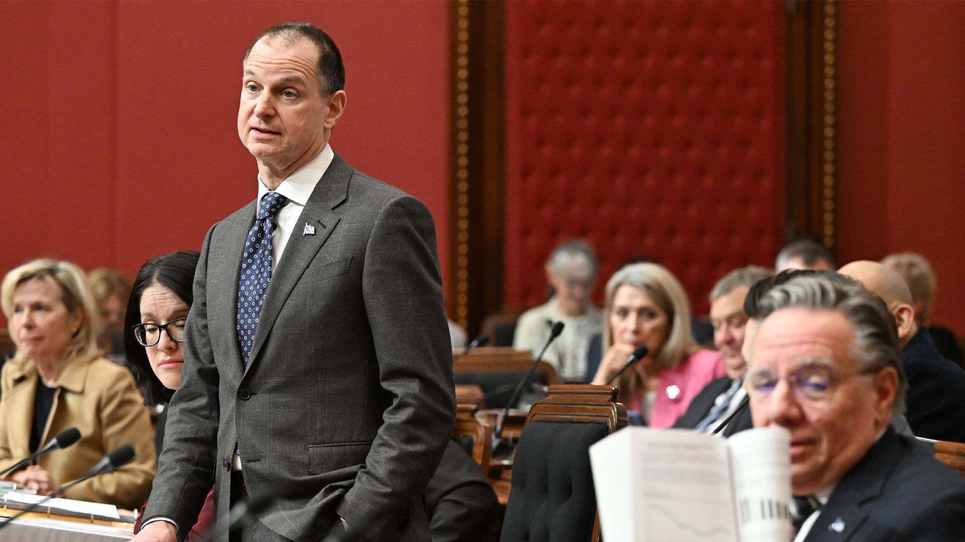 Le ministre des Finances du Québec, Éric Girard, répond à l'opposition sur son budget alors que le premier ministre du Québec, François Legault, à gauche, montre une page du discours sur le budget à un collègue pendant la période de questions à l'Assemblée législative à Québec.