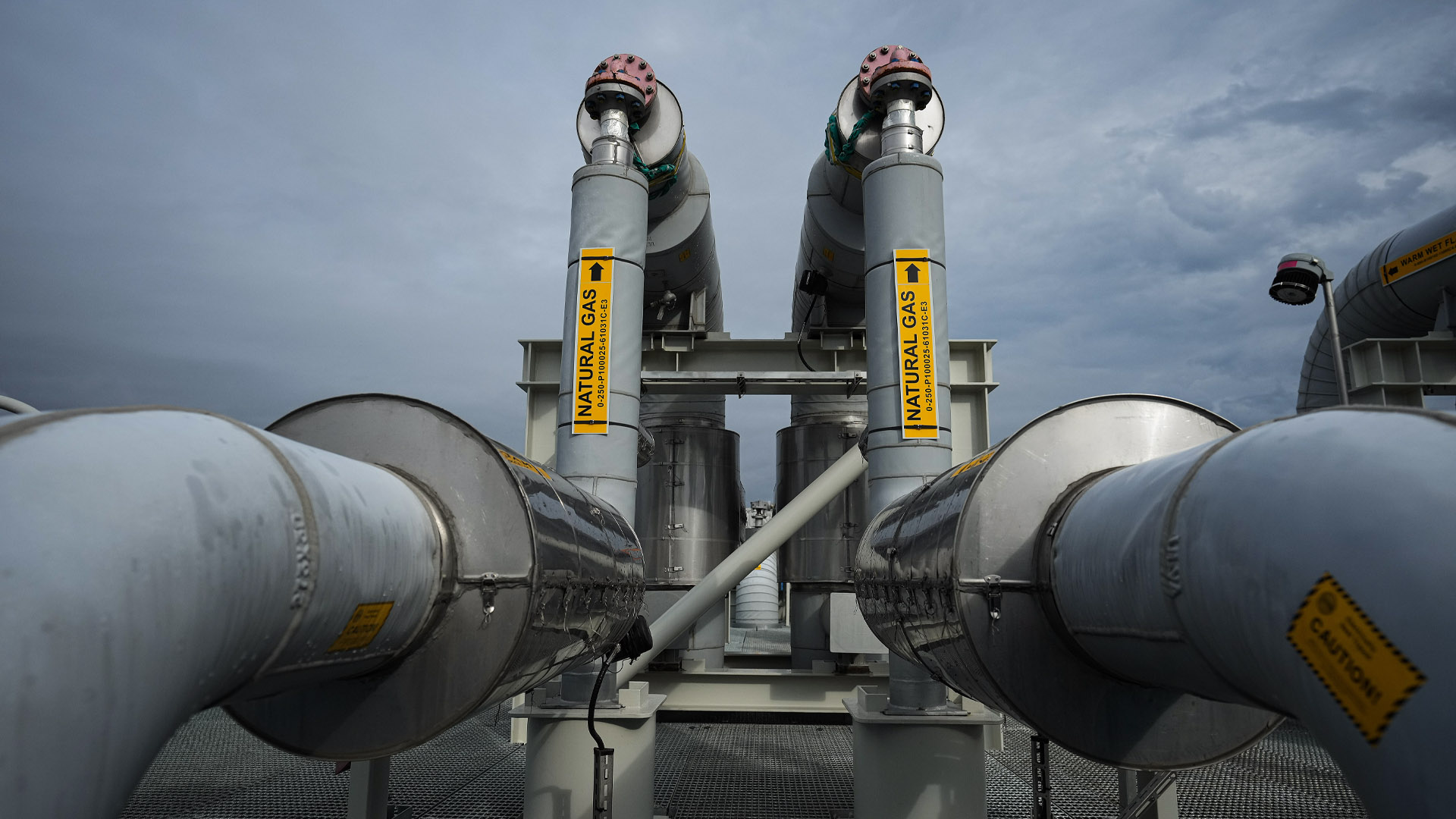 Twin elbowed pipes with “natural gas” written on yellow signs.