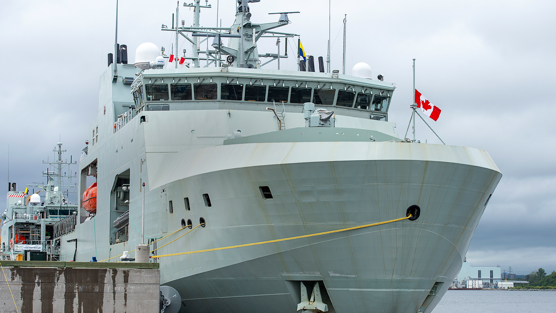It’s a ship that is light-grey metal and is tied up at a concrete dock.