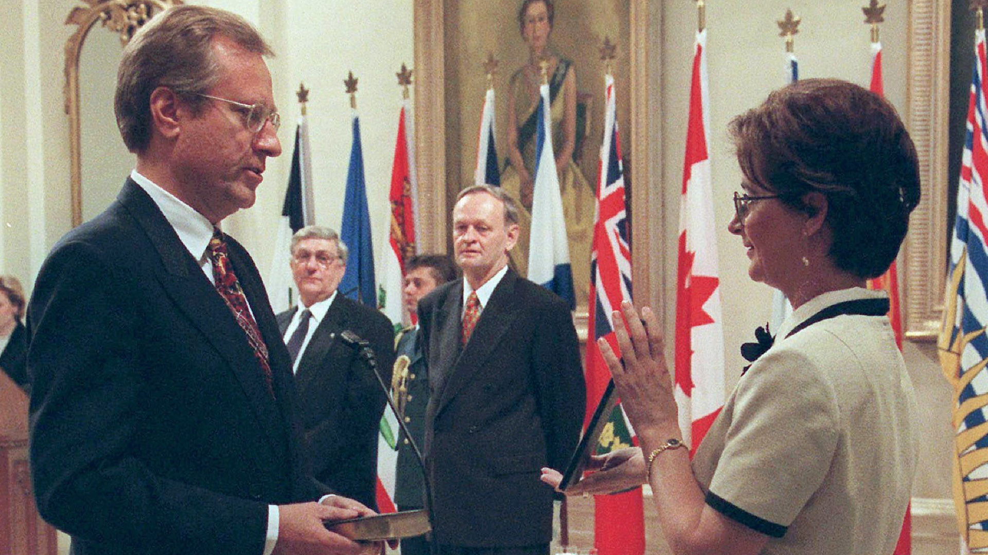 Jocelyne Bourgon tient le texte du serment devant le ministre, qui tient la Bible. Le gouverneur général Roméo LeBlanc et le premier ministre Jean Chrétien observent la scène, sous un portrait de la reine Elizabeth.