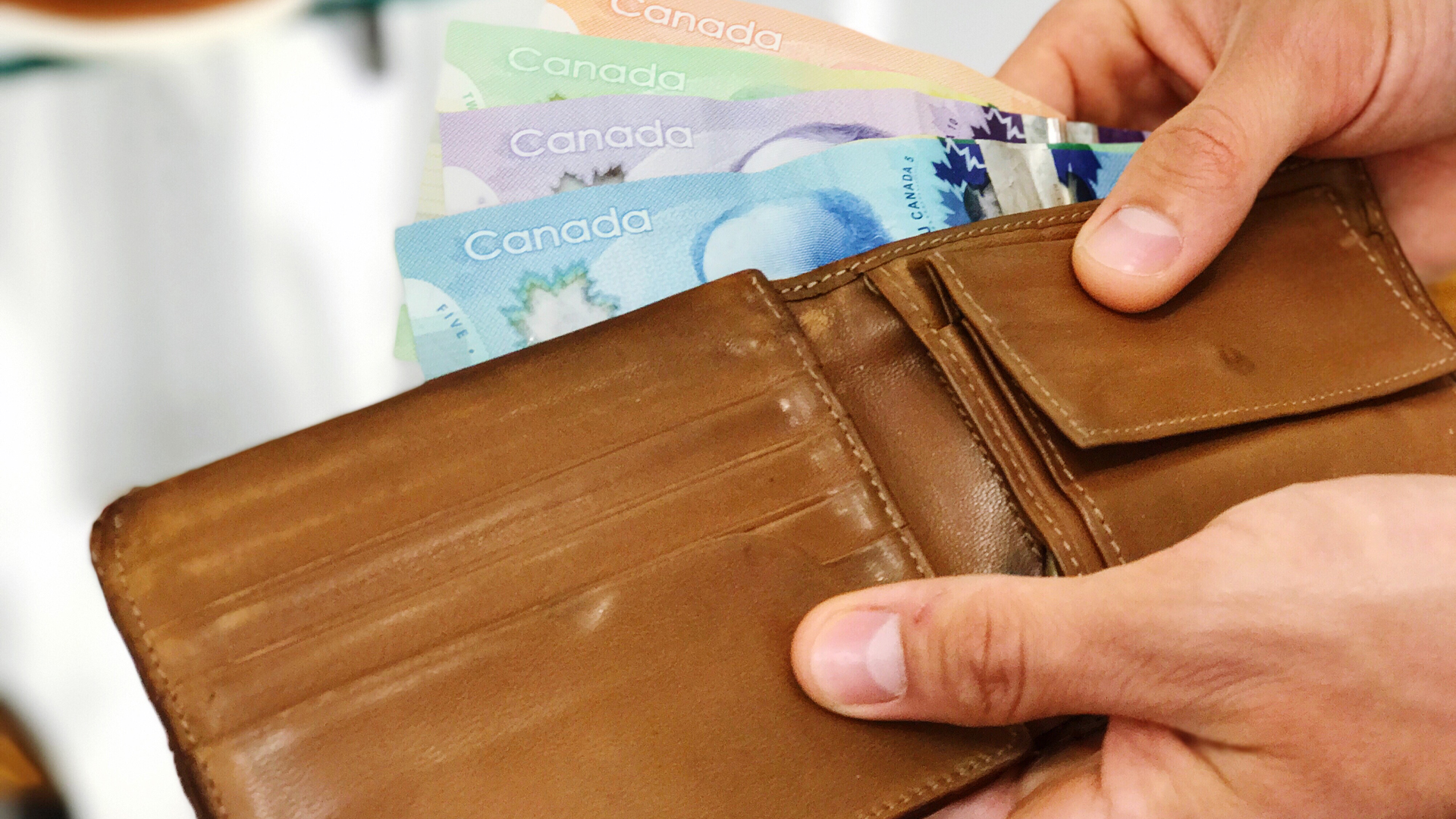 Canadian currency being pulled out of a wallet.